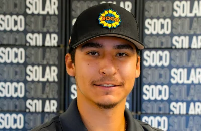 A man wearing a black SOCO Solar cap and polo shirt stands in front of a background with the words "SOCO" and "SOLAR" repeated.