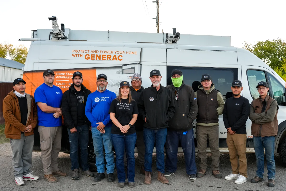A group of eleven people stand in front of a work van with Generac branding, posing for a photo outdoors.